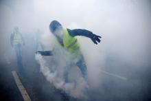Gelbweste wirft eine Tränengasgranate zurück