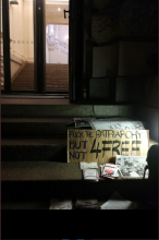 Foto einer Treppe auf der ein Schild lehnt mit der Aufschrit: Fuck the patriarchy but not for free