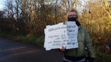 Person mit Schild: Gerichtsvollzieher*innen schützen die Reichen und den Staat und machen Arme noch ärmer. Voll Scheiße!