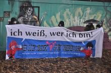 Transpi beim IDAHOBIT in Freiburg. Spruch: "Ich weiß, wer ich bin. Wer dich negiert, spürt unseren Zorn. solidarische trans*inter*non-binary selbstverteidigung
