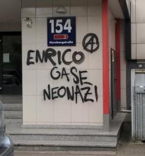 Am Eingangsbereich eines Plattenbaus in der Herzbergstraße steht in großen Schwarzen Buchstaben: "Enrico Gase Neonazi". Daneben ein eingekreistes A.