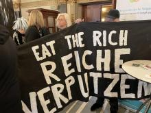 Banner in der Wuppertaler Stadthalle mit dem Text "EAT THE RICH - REICHE VERPUTZEN"