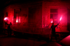 Menschen halten vor einem Haus ein Transparent mit der Aufschrift "Antischocke lebt!" und zwei brennende Bengalos hoch
